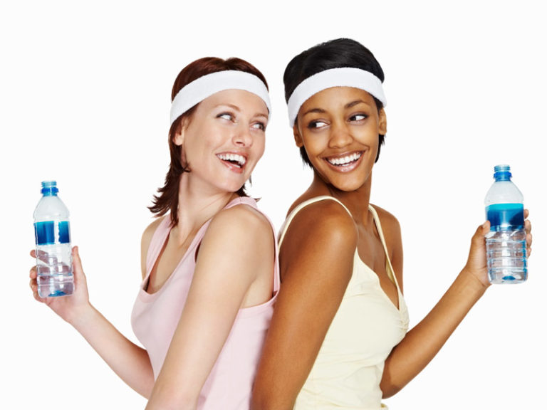 Two friendly women drinking water together after a workout.