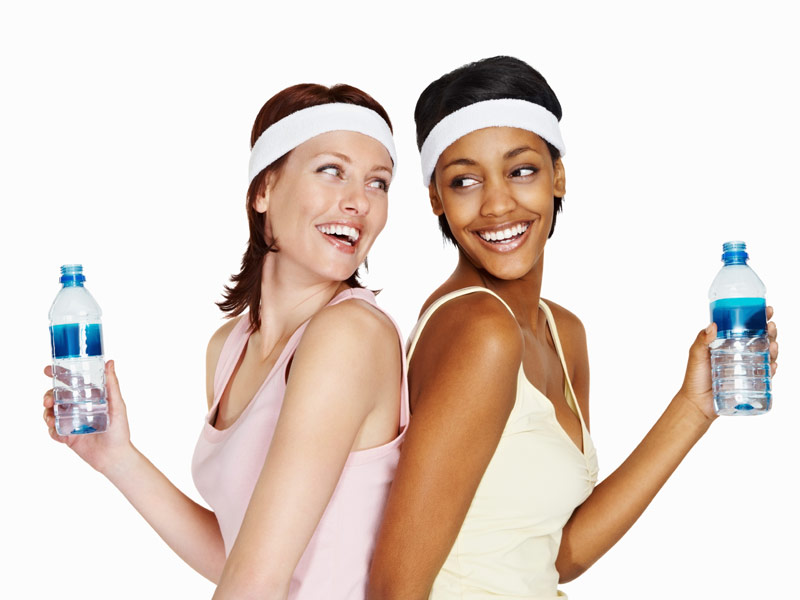 Two friendly women drinking water together after a workout.