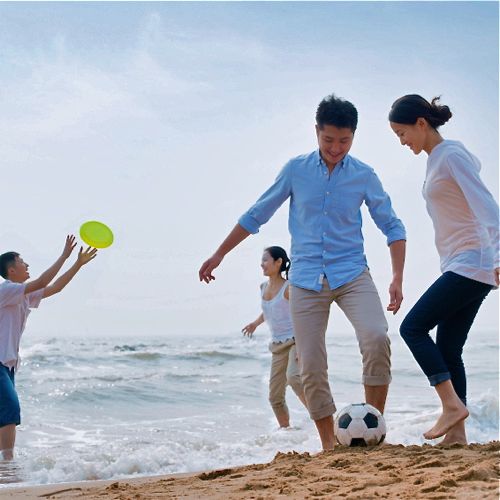 family on beach playing soccer and frisbee