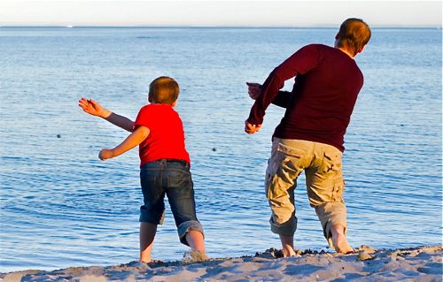 Father and son skip stones on water